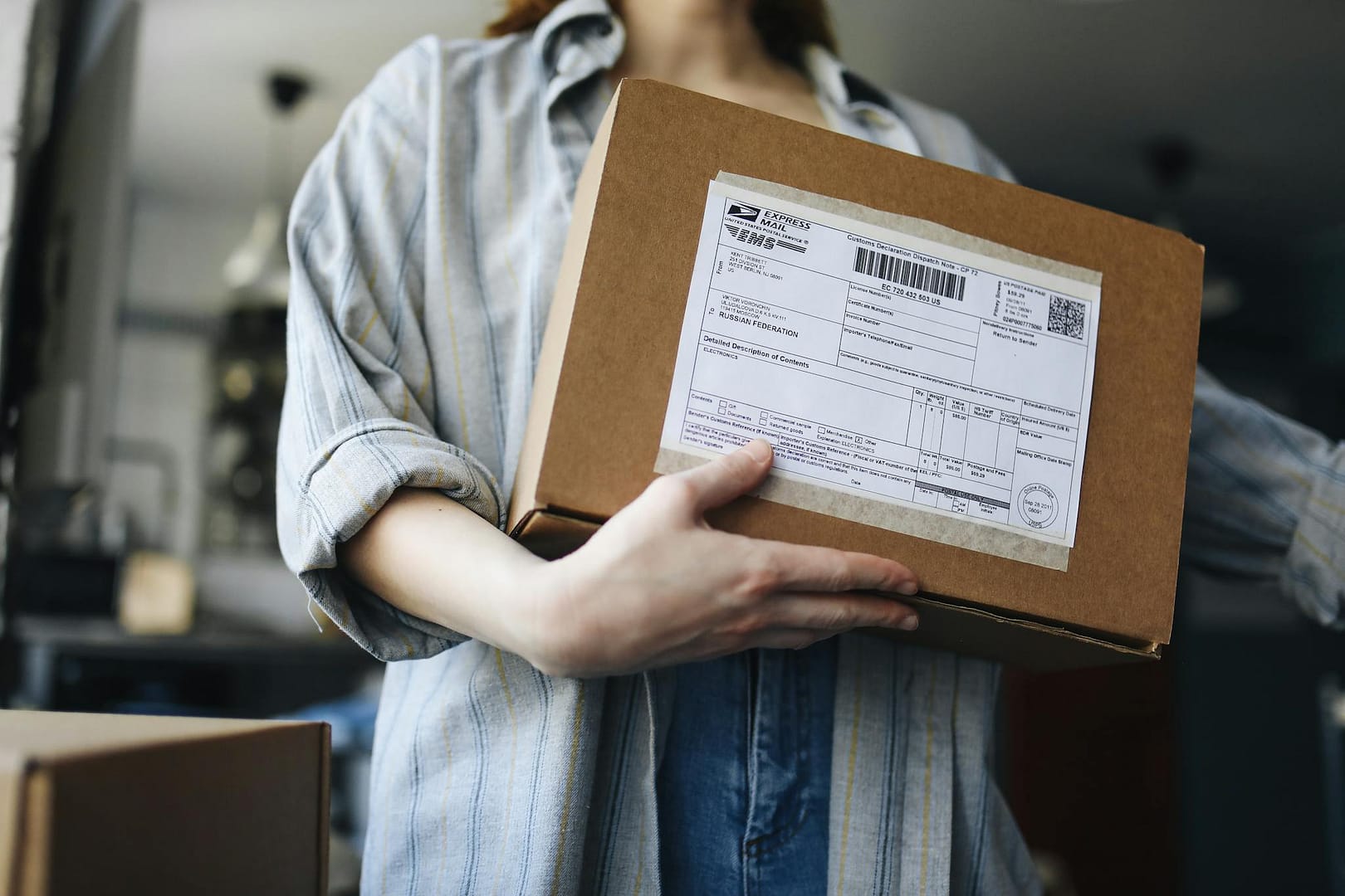 Close-up of a woman holding a parcel indoors, showcasing postal and delivery themes.